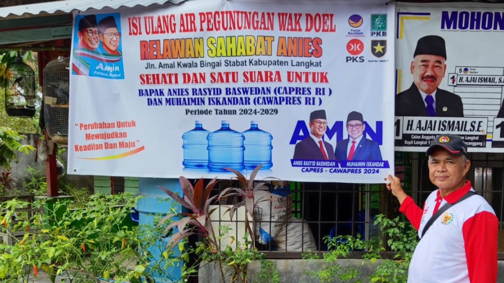 Sekretaris Eksekutif Sahabat Anies Sumut Drs Harun Al Rasyid di depan warung dengan spanduk pasangan bacapres Anies-Muhaimin di Stabat Langkat (portalswara.com/dok)